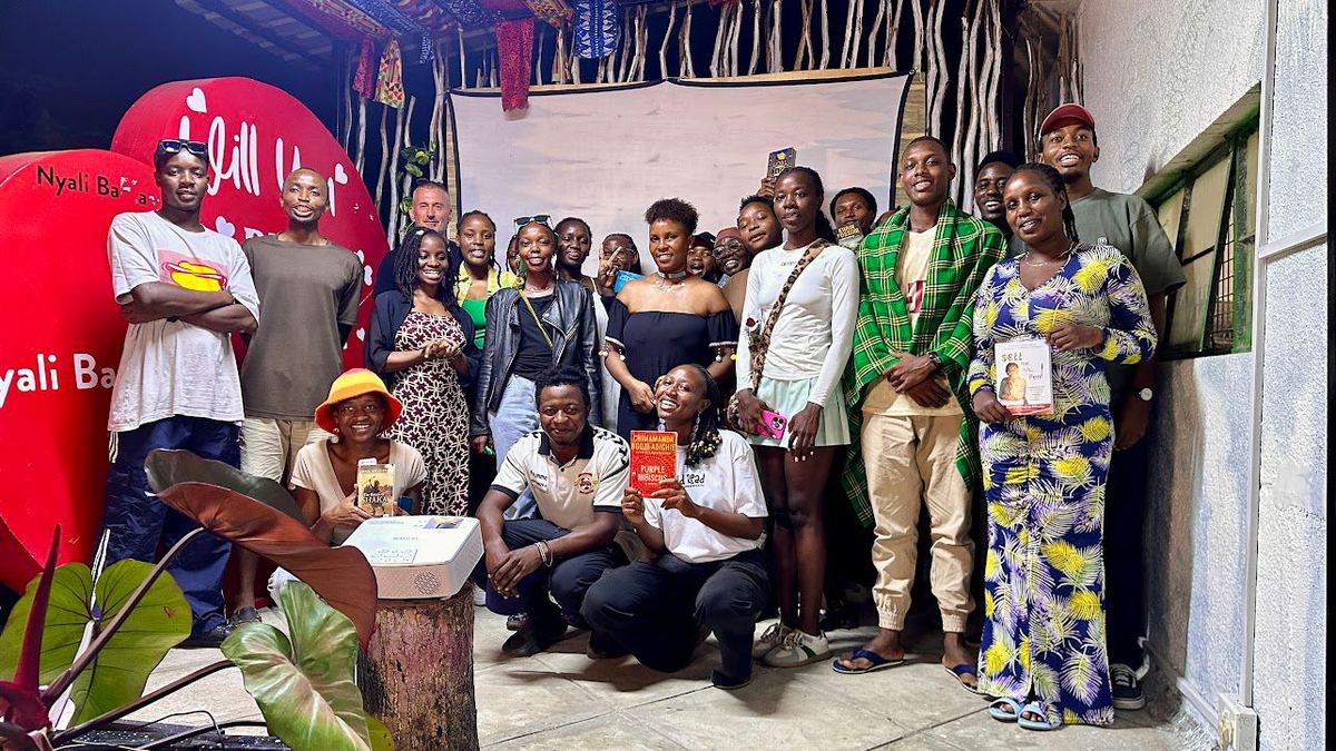 A large group of participants gathered together for a photograph at the end of an evening event, some holding books.
