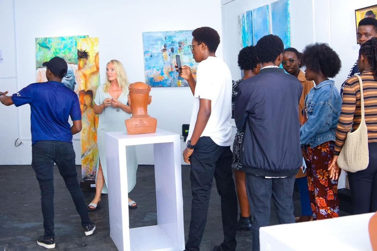Visitors gathered around a terracotta bust on a plinth in the gallery, one of them photographing it.